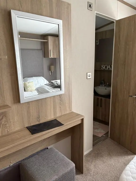 a bathroom with a mirror and a sink and a bed at Sunset villa in Lossiemouth