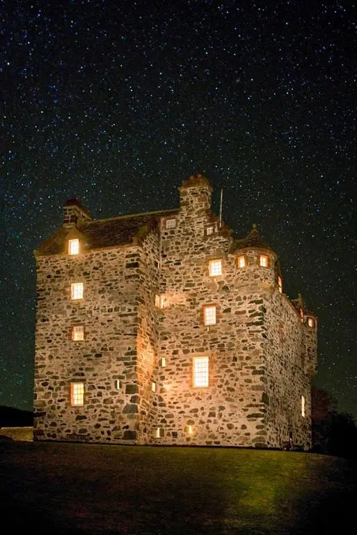 a large stone building with lights on it at night at The Fortalice in Tulchan