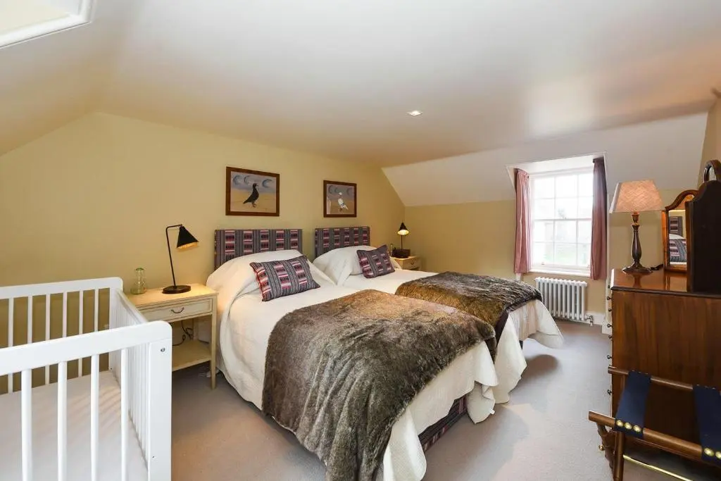 a bedroom with two beds and a window at Spey Valley House in Ruthven