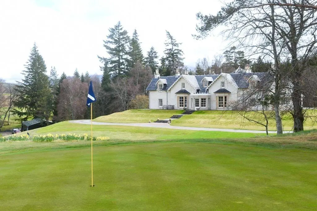 a golf green with a house in the background at Spey Valley House in Ruthven