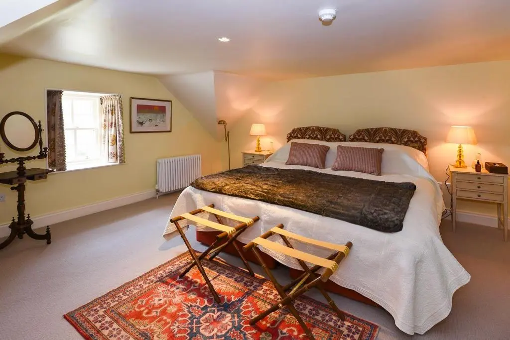 a bedroom with a large bed and two chairs at Spey Valley House in Ruthven