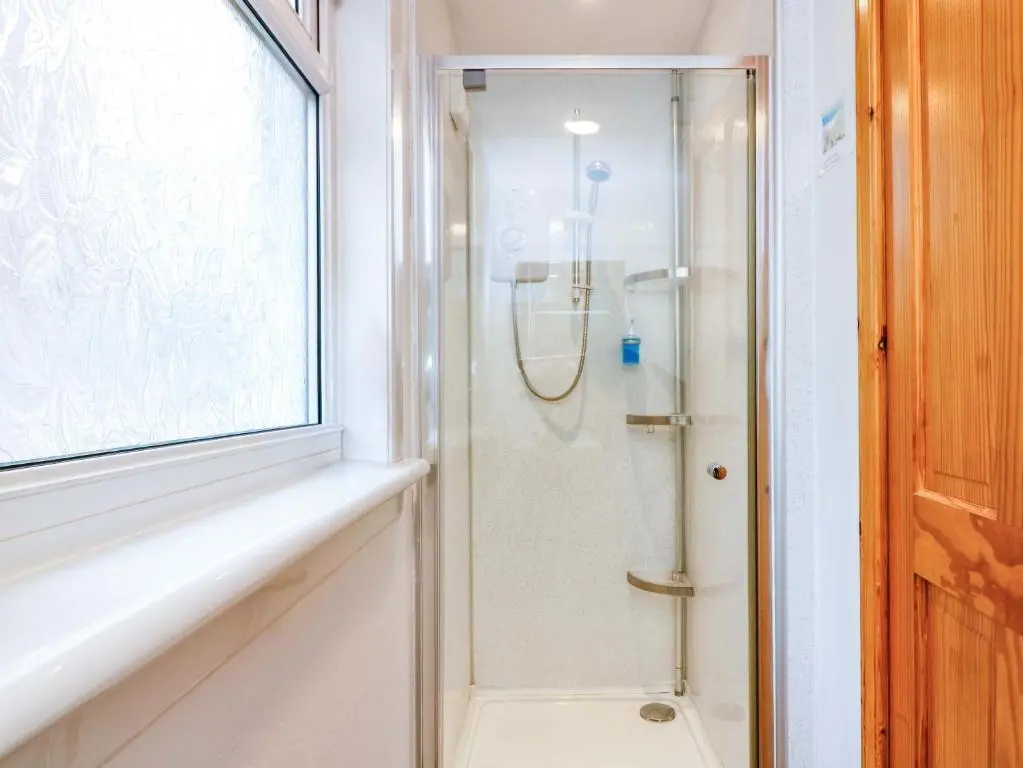 a bathroom with a shower with a glass door at Rose Cottage in Nairn