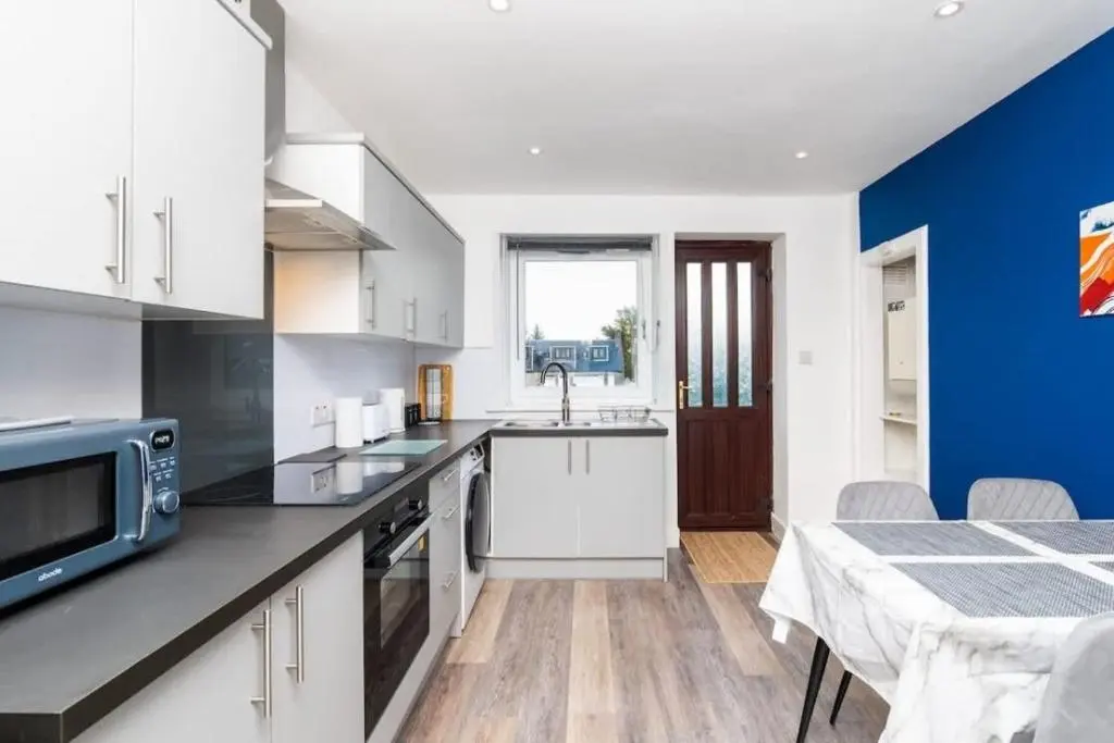 a kitchen with white cabinets and a blue wall at Aberdeen Airport Cozy Apartment - 3 Beds - Sleeps 5 with Free Parking and Fast Wi-Fi in Aberdeen
