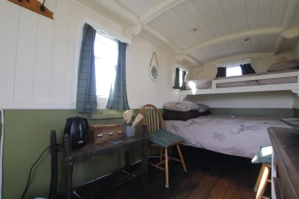 a small room with a bed and a desk and a bunk bed at The Rumster Hut in Lybster