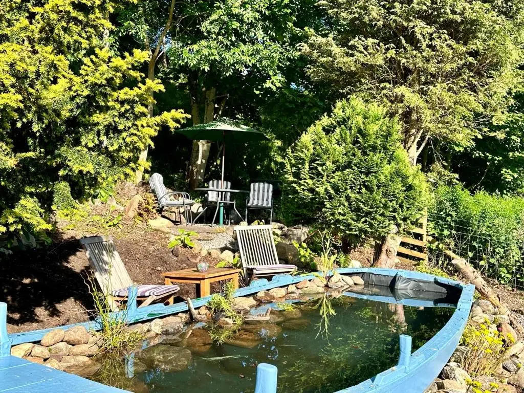 a garden with a pond and two chairs and a table at Glenshee Suite, Beechtree Cottage in Kirkmichael