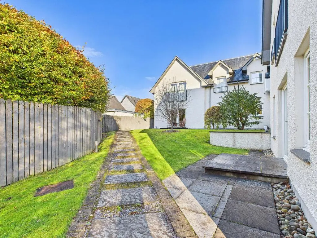 a backyard with a fence and a grass yard at The Steadings Aviemore Premium Highland Apartment Near Cairngorms & Town Centre in Aviemore