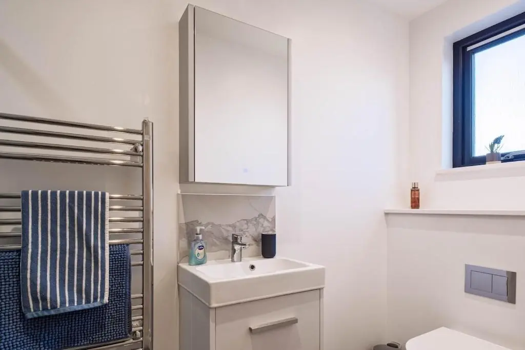 a white bathroom with a sink and a mirror at Modern Central Apartment Huntly in Huntly
