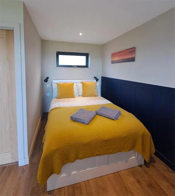 a bedroom with a bed with a yellow blanket at Lothmore Lookout - Sunrise in Kilmote