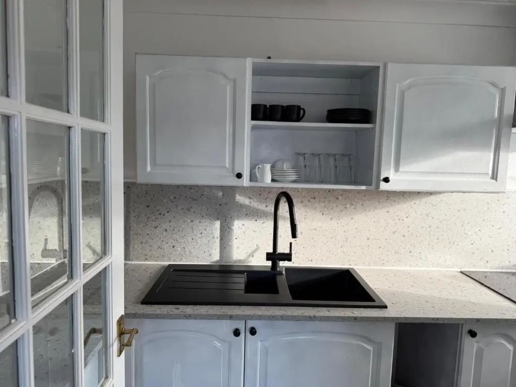 a kitchen with a sink and white cabinets at Nessy5 Apartment in Inverness