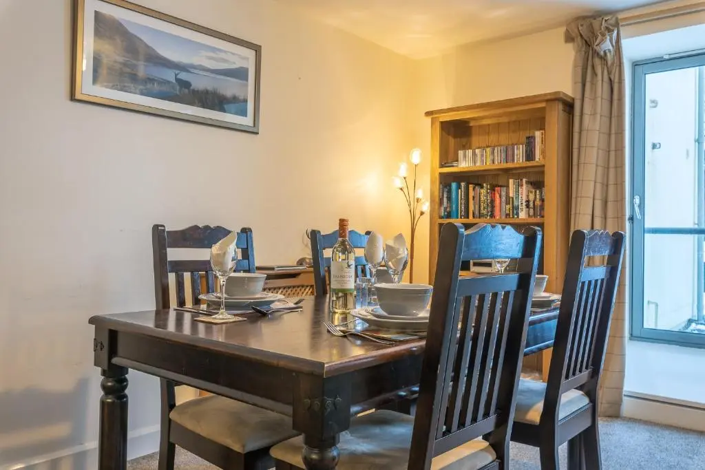 a dining room with a wooden table and chairs at Torr Apartment Raven in Fort Augustus