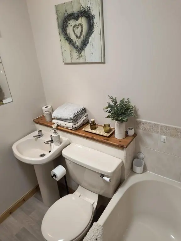 a bathroom with a white toilet and a sink at Highland Getaway in Inshes