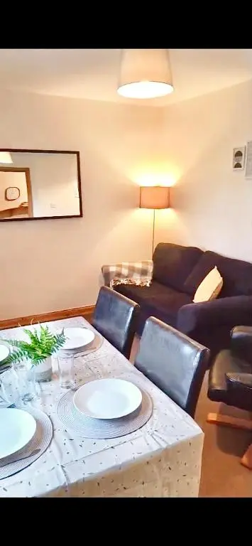 a living room with a table and a couch at Highland Getaway in Inshes