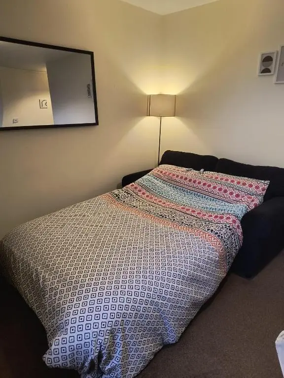 a bed in a room with a lamp on the wall at Highland Getaway in Inshes