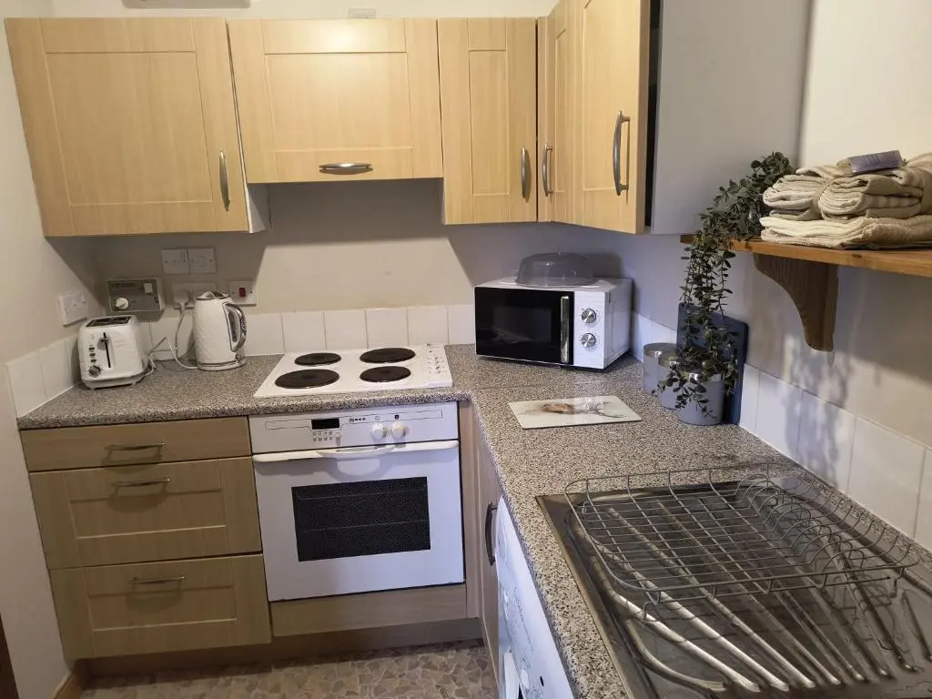 a small kitchen with a stove and a microwave at Highland Getaway in Inshes