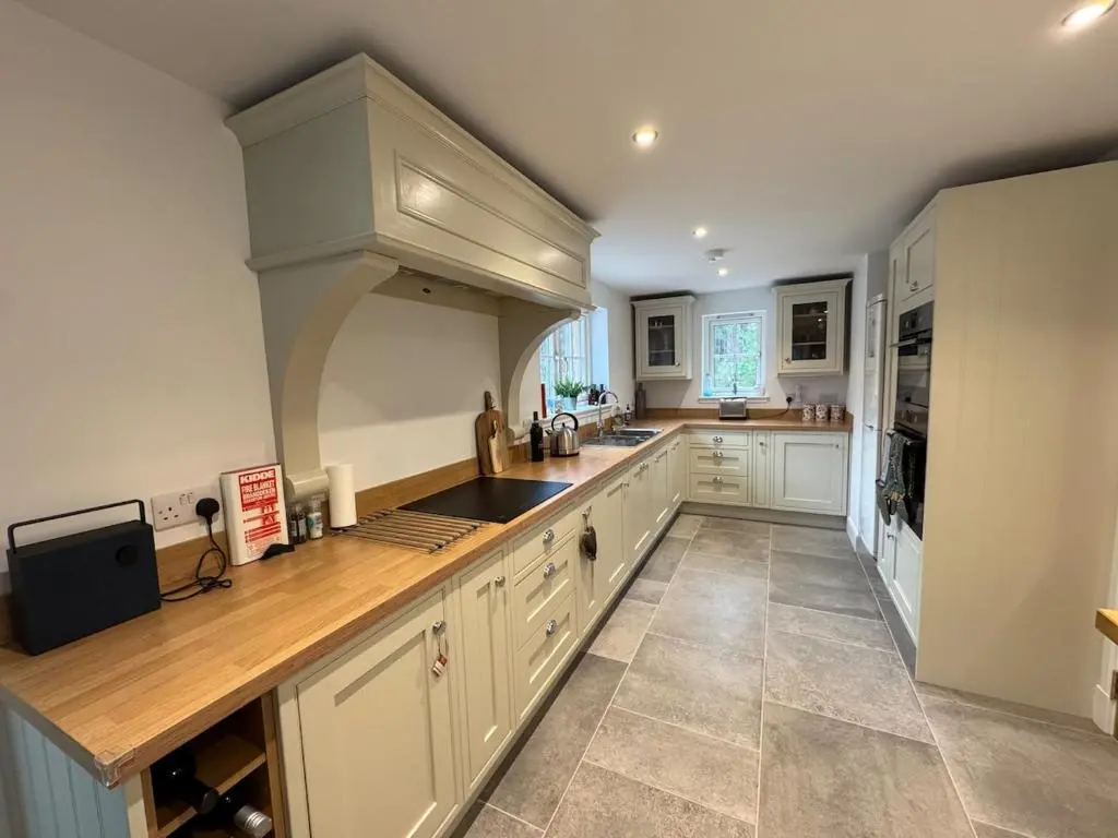 a kitchen with white cabinets and wooden counter tops at Cosy Highland Cottage in the Woods on Royal Deeside in Coldstone