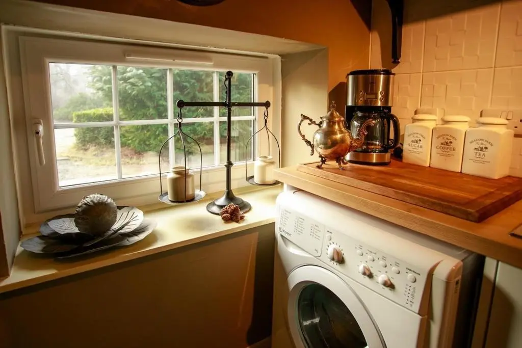 a kitchen with a washing machine and a window at Bliss Cottage in Nairn