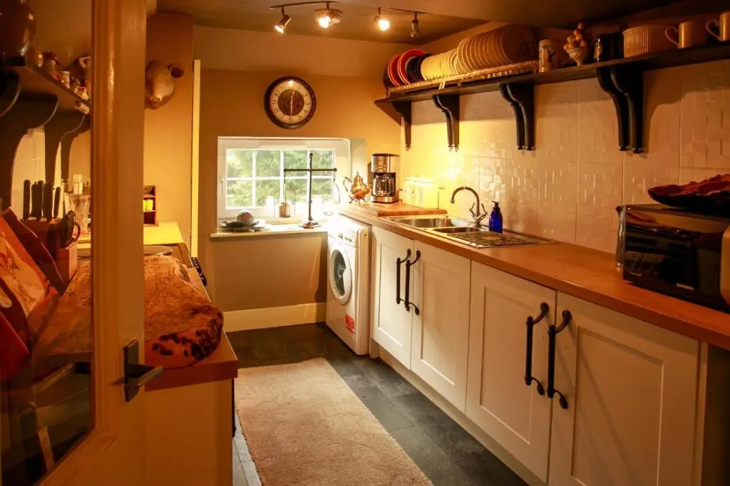 a kitchen with a sink and a washing machine at Bliss Cottage in Nairn