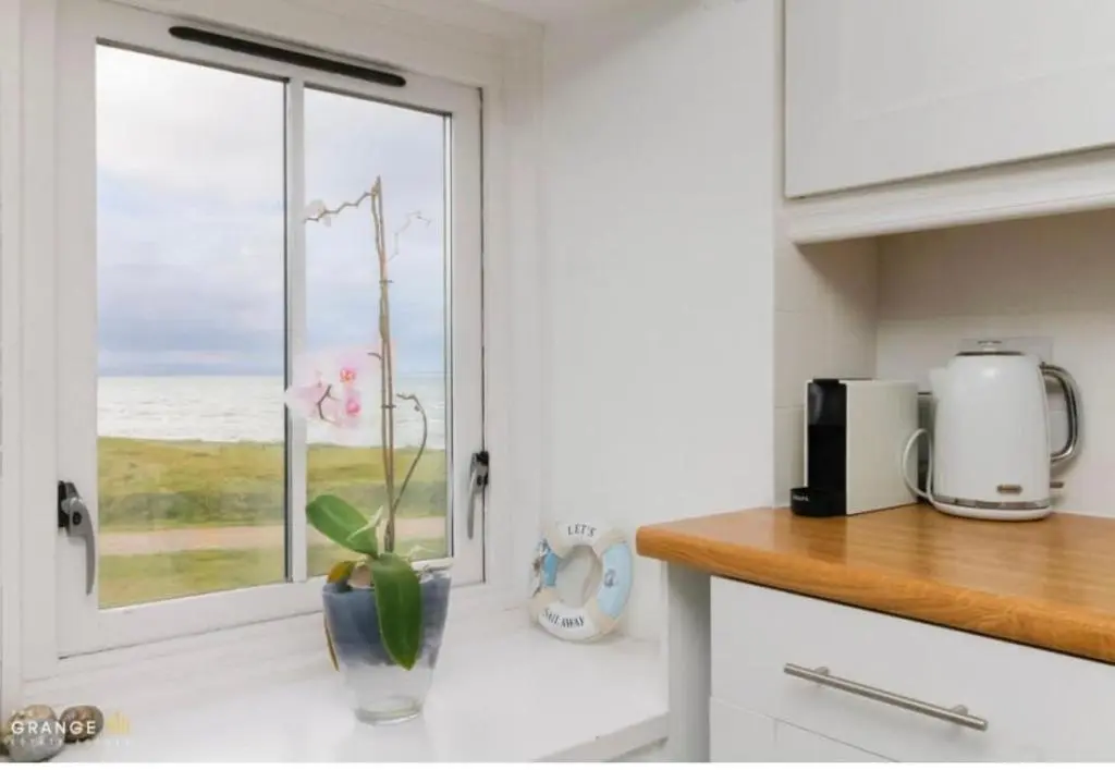 a kitchen with a vase with a flower in a window at The Beach Flat in Burghead
