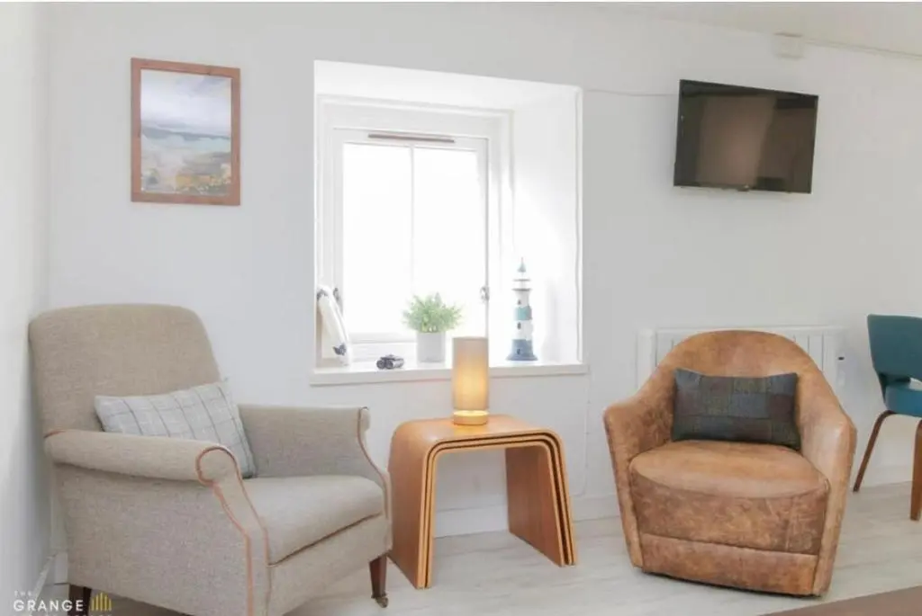 a living room with two chairs and a table at The Beach Flat in Burghead
