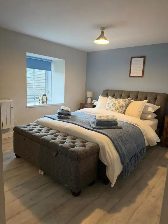 a bedroom with a large bed and a ottoman at The Beach Flat in Burghead