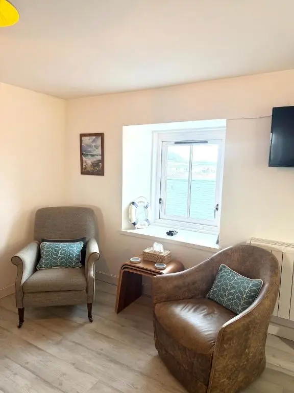 a living room with a couch and a chair and a window at The Beach Flat in Burghead