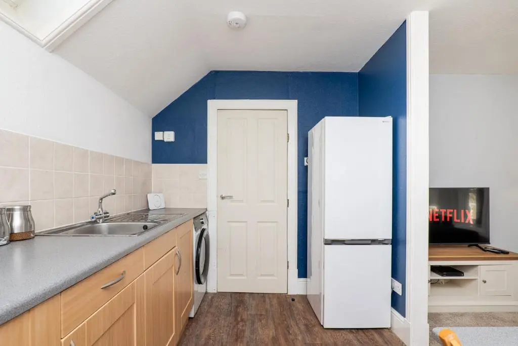 a kitchen with a white refrigerator and a sink at Charming 1-Bed Coastal Cottage by Holiday Homes in Portgordon