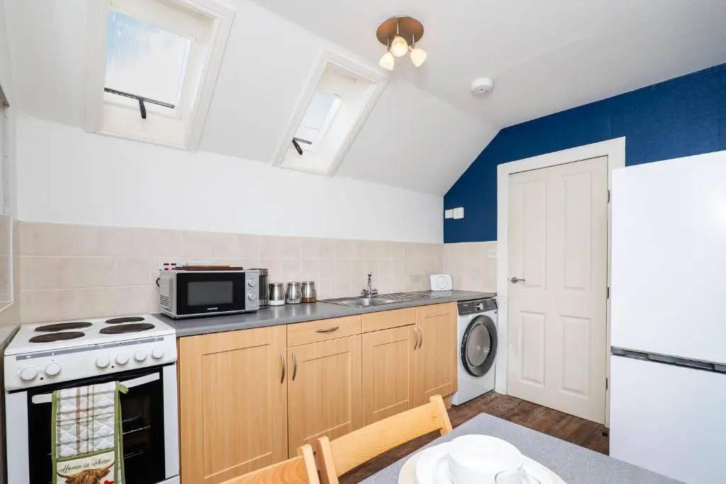 a kitchen with a stove and a microwave at Charming 1-Bed Coastal Cottage by Holiday Homes in Portgordon