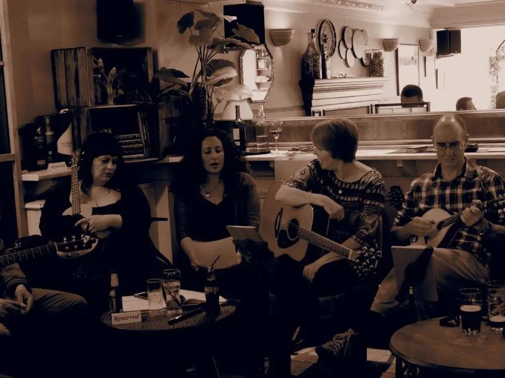 a group of people sitting in a room playing guitars at The Dundonnell Hotel in Dundonnell