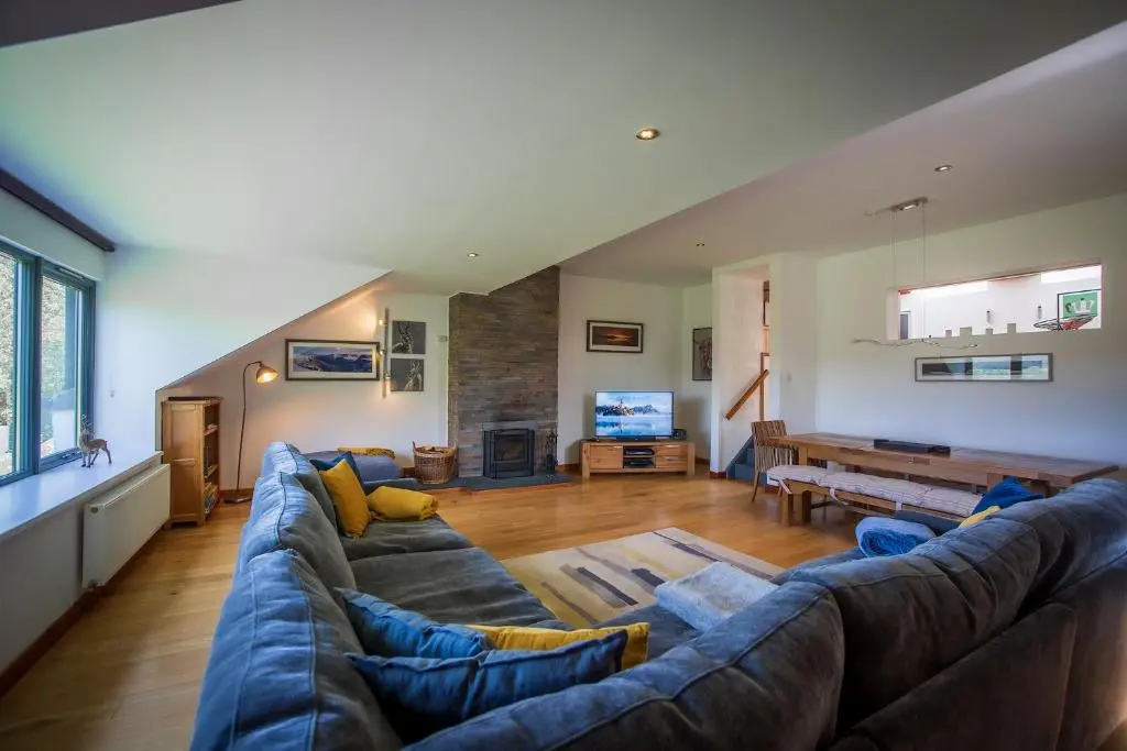 a large living room with a large blue couch at Kirkstone Lodge in Insh