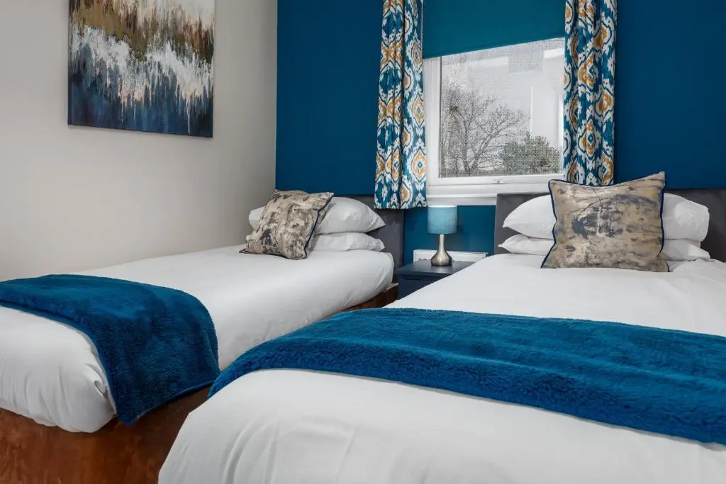two beds in a room with blue walls at Castle Heather 2 Bedroom Holiday Home in Inshes