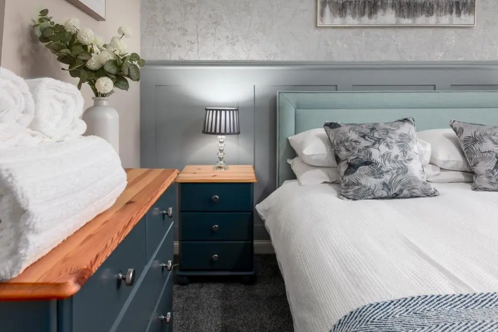 a bedroom with two beds and a table with a lamp at Castle Heather 2 Bedroom Holiday Home in Inshes