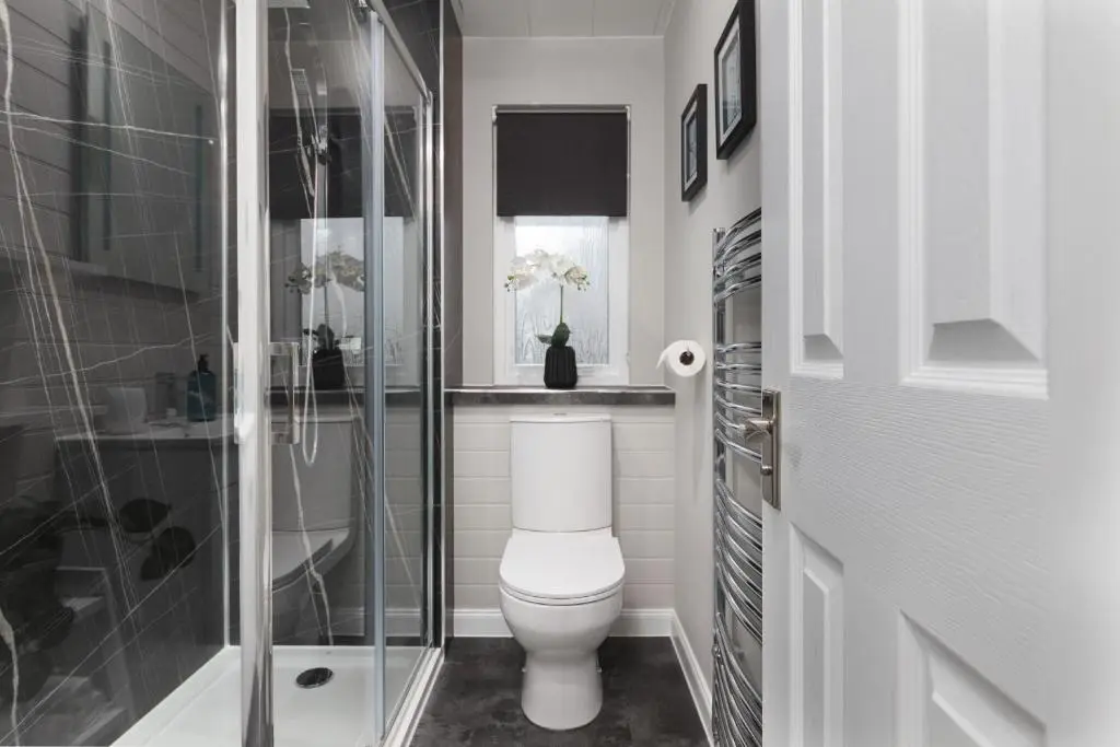 a white bathroom with a toilet and a shower at Castle Heather 2 Bedroom Holiday Home in Inshes