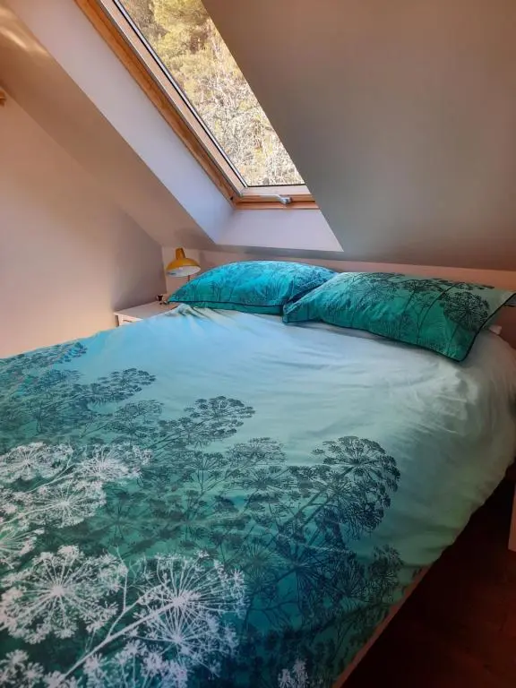 a bedroom with a bed with a blue comforter at The Wee Loft in Carrbridge