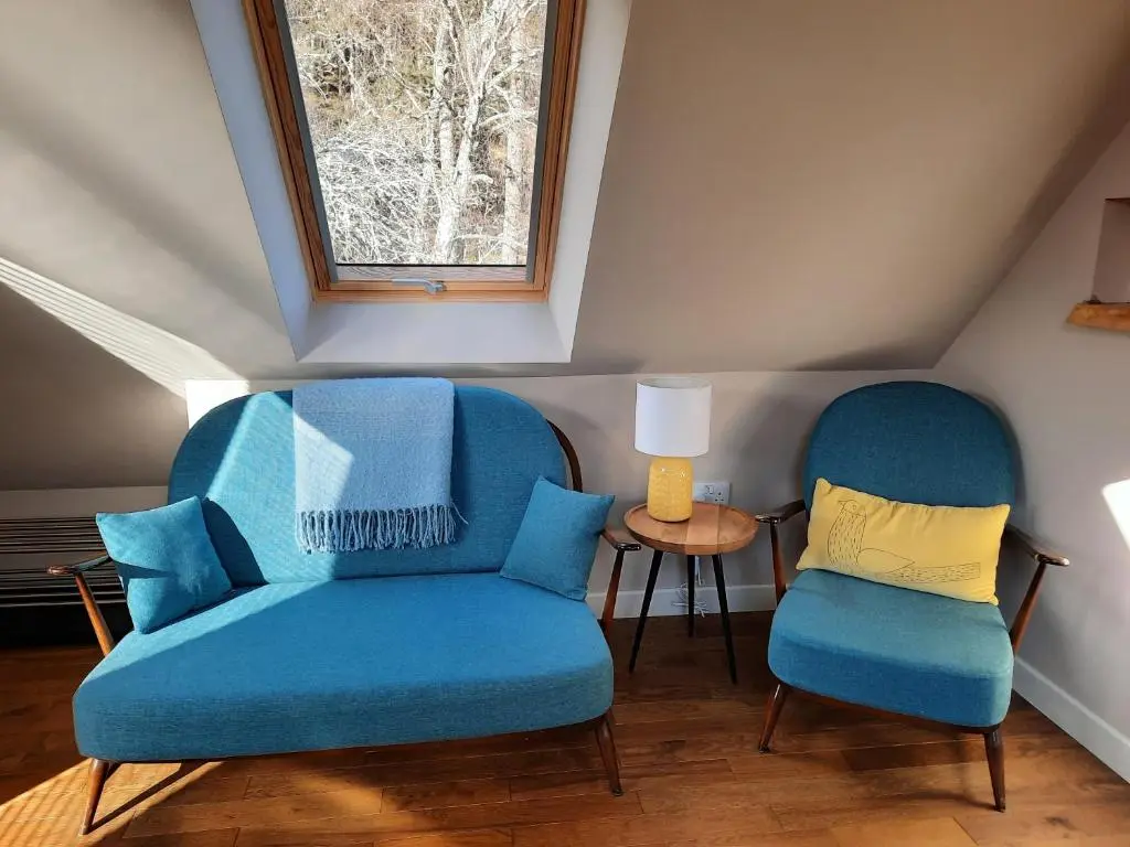 two blue chairs and a table in a room at The Wee Loft in Carrbridge