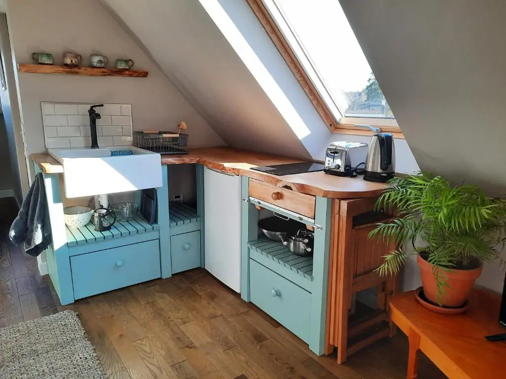 a kitchen with a sink and a desk in a attic at The Wee Loft in Carrbridge