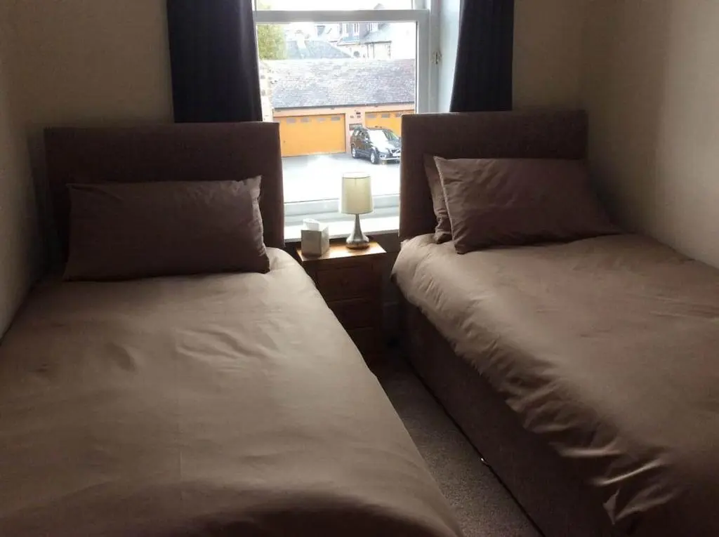 two twin beds in a room with a window at Macdonald Apartment 11C Greig St Inverness IV3 5PT in Inverness