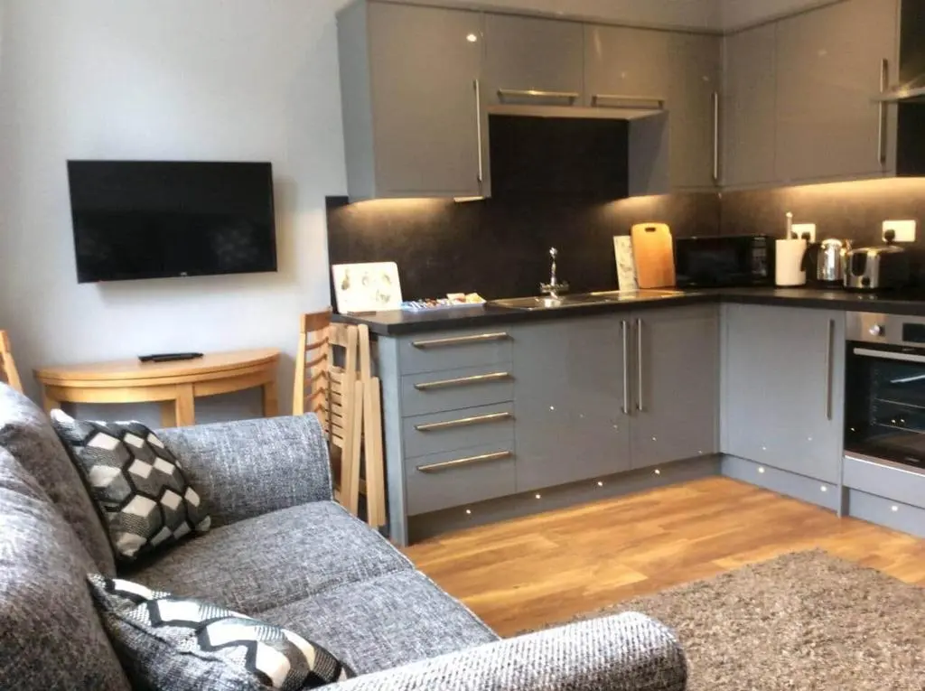 a living room with a couch and a kitchen at Macdonald Apartment 11C Greig St Inverness IV3 5PT in Inverness