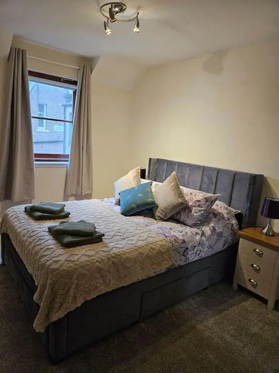 a bedroom with a bed with pillows and a window at 5 Ardross Court, 20 Ardross St. Inverness IV3 5NH in Inverness