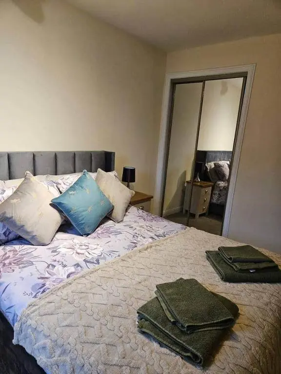 a bedroom with a bed with towels and a mirror at 5 Ardross Court, 20 Ardross St. Inverness IV3 5NH in Inverness