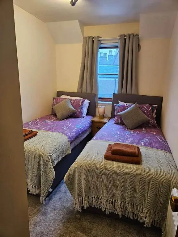 a bedroom with two beds and a window at 5 Ardross Court, 20 Ardross St. Inverness IV3 5NH in Inverness