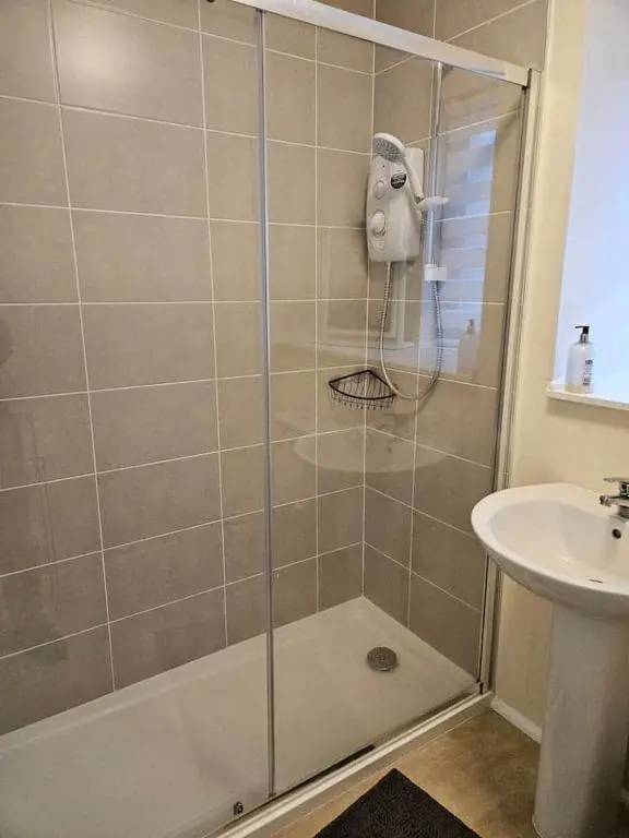 a shower with a glass door next to a sink at 5 Ardross Court, 20 Ardross St. Inverness IV3 5NH in Inverness