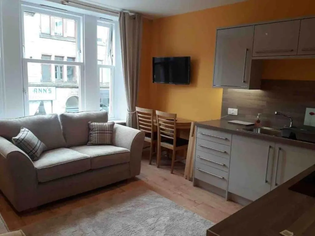 a living room with a couch and a kitchen at Macdonald Apartments 9C Greig St Inverness IV3 5PT in Inverness