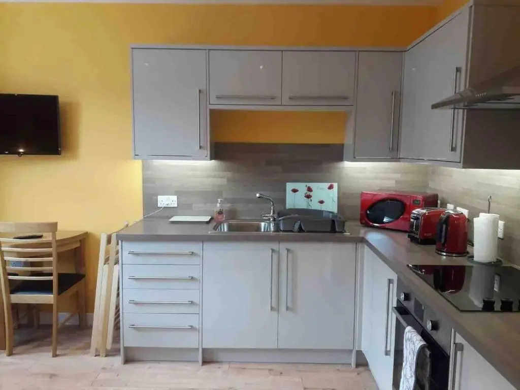 a kitchen with white cabinets and a sink at Macdonald Apartments 9C Greig St Inverness IV3 5PT in Inverness
