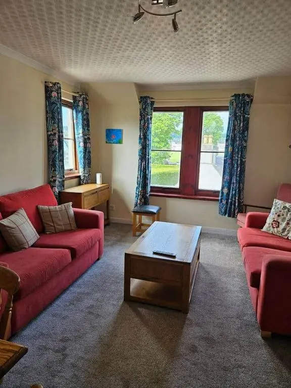 a living room with red couches and a coffee table at 8 Ardross Court 20 Ardross St. Inverness IV3 5NH in Inverness