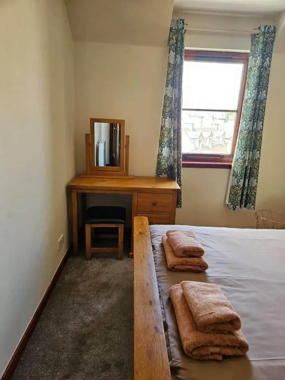 a bedroom with a bed and a desk and a mirror at 8 Ardross Court 20 Ardross St. Inverness IV3 5NH in Inverness