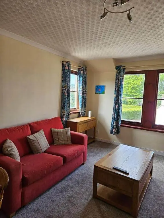 a living room with a red couch and a coffee table at 8 Ardross Court 20 Ardross St. Inverness IV3 5NH in Inverness