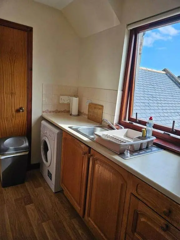 a kitchen with a sink and a washing machine at 8 Ardross Court 20 Ardross St. Inverness IV3 5NH in Inverness