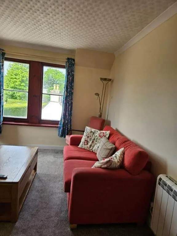 a living room with a red couch and a window at 8 Ardross Court 20 Ardross St. Inverness IV3 5NH in Inverness