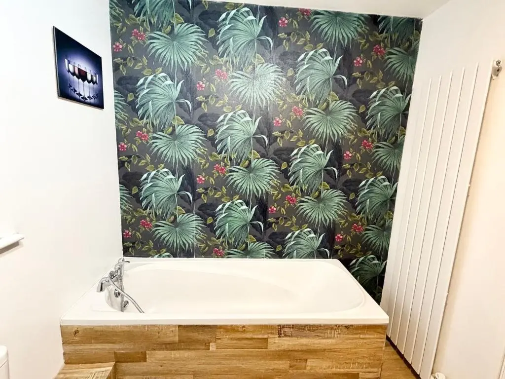 a bath tub in a bathroom with a tropical wallpaper at Mamore House Inverness in Dalneigh