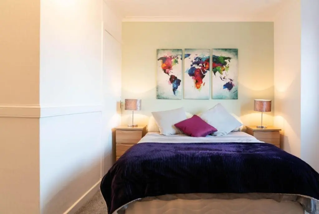 a bedroom with a bed with two paintings on the wall at Dunedin House in Huntly